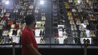 Pengunjung mengamati instalasi sepatu pada acara Urban Sneaker Society 2021 di Jakarta Convention Center, Senayan, Jakarta, Minggu (5/12/2021). [Suara.com/Angga Budhiyanto]