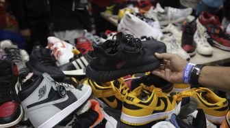 Pengunjung memilih produk yang ditawarkan pada acara Urban Sneaker Society 2021 di Jakarta Convention Center, Senayan, Jakarta, Minggu (5/12/2021). [Suara.com/Angga Budhiyanto]