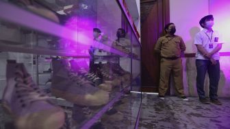 Penjaga berdiri di depan 'booth' sepatu pada acara Urban Sneaker Society 2021 di Jakarta Convention Center, Senayan, Jakarta, Minggu (5/12/2021). [Suara.com/Angga Budhiyanto]