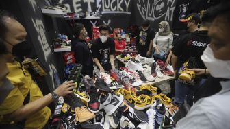 Pengunjung mengamati produk yang ditawarkan pada acara Urban Sneaker Society 2021 di Jakarta Convention Center, Senayan, Jakarta, Minggu (5/12/2021). [Suara.com/Angga Budhiyanto]