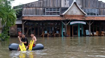 Warga menaiki kasur angin untuk menerobos banjir yang menggenangi kawasan Legian, Kuta, Badung, Bali, Senin (6/12/2021). ANTARA FOTO/Fikri Yusuf