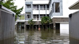 Warga berjalan menerobos banjir yang menggenangi apartemen di kawasan Legian, Kuta, Badung, Bali, Senin (6/12/2021). ANTARA FOTO/Fikri Yusuf
