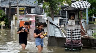 Warga berjalan menerobos banjir yang menggenangi kawasan Legian, Kuta, Badung, Bali, Senin (6/12/2021).   ANTARA FOTO/Fikri Yusuf