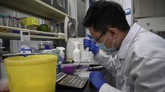 Seorang teknisi laboratorium bekerja di laboratorium Universitas Tsinghua, Beijing, China, pada (9/12/2021). [NOEL CELIS / AFP]