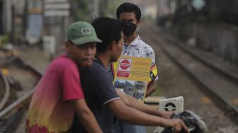 Relawan dari komunitas Railfans melakukan sosialisasi keselamatan di perlintasan sebidang Bukit Duri, Jakarta, Sabtu (11/12/2021). [Suara.com/Angga Budhiyanto]