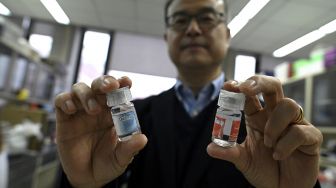 Profesor Fakultas Kedokteran Universitas Tsinghua, Zhang Linqi menunjukkan dua antibodi monoklonal di laboratorium Universitas Tsinghua, Beijing, China, pada (9/12/2021). [NOEL CELIS / AFP]