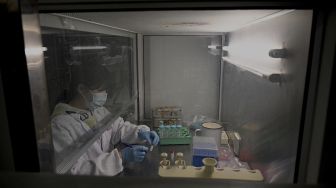 Seorang teknisi laboratorium bekerja di laboratorium Universitas Tsinghua, Beijing, China, pada (9/12/2021). [NOEL CELIS / AFP]