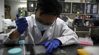 Seorang teknisi laboratorium bekerja di laboratorium Universitas Tsinghua, Beijing, China, pada (9/12/2021). [NOEL CELIS / AFP]