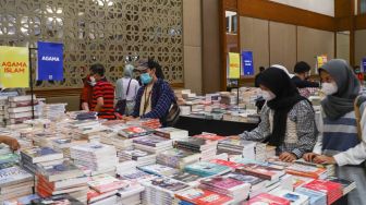 Pengunjung memilih buku dalam pameran Indonesia Internationa Book Fair (IIBF) 2021 di JCC Senayan, Jakarta Pusat, Minggu (12/12/2021). [Suara.com/Alfian Winanto]