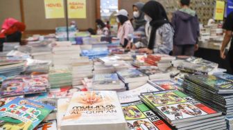 Pengunjung memilih buku dalam pameran Indonesia Internationa Book Fair (IIBF) 2021 di JCC Senayan, Jakarta Pusat, Minggu (12/12/2021). [Suara.com/Alfian Winanto]
