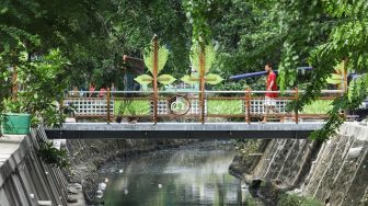 Warga melintasi jembatan di Jalan Galur Sari Timur, Matraman, Jakarta Timur, Senin (13/12/2021). [Suara.com/Alfian Winanto]