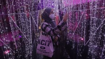 Pengunjung berswafoto di dalam dekorasi perayaan Natal bertema "A Shining Shimmering Christmas" di Mal Grand Indonesia, Jakarta, Senin (13/12/2021). [Suara.com/Angga Budhiyanto]