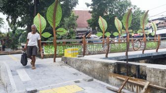 Warga melintasi jembatan di Jalan Galur Sari Timur, Matraman, Jakarta Timur, Senin (13/12/2021). [Suara.com/Alfian Winanto]