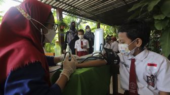 Tenaga kesehatan memeriksa kondisi kesehatan pelajar sebelum mendapatkan vaksin COVID-19 di SDN 04 Cilandak Barat, Jakarta, Selasa (14/12/2021). [Suara.com/Angga Budhiyanto]