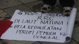 Massa yang tergabung dalam Forum Cinta Tanah Air menginjak poster berisi protes saat melakukan aksi unjuk rasa di depan Kedubes Republik Rakyat China (RRC), Jakarta, Rabu (15/12/2021). [Suara.com/Angga Budhiyanto]