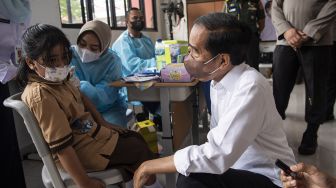 Presiden Joko Widodo (kanan) menyaksikan seorang anak yang akan menjalani vaksinasi COVID-19 di Kompleks SDN Cideng, Gambir, Jakarta Pusat, Rabu (15/12/2021).  ANTARA FOTO/Sigid Kurniawan
