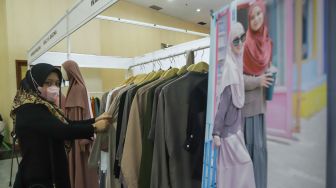 Pengunjung memilih pakaian di acara Muslima Festival 2021 di Smesco Indonesia, Jakarta Selatan, Sabtu (18/12/2021). [Suara.com/Alfian Winanto]