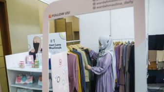 Pengunjung memilih pakaian di acara Muslima Festival 2021 di Smesco Indonesia, Jakarta Selatan, Sabtu (18/12/2021). [Suara.com/Alfian Winanto]