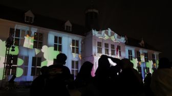 Sejumlah pengunjung melihat video mapping bernuansa Natal yang ditampilkan dalam acara 'Christmas in Jakarta' di Museum Fatahillah, Kota Tua, Jakarta, Minggu (19/12/2021). [Suara.com/Angga Budhiyanto]