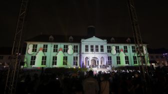 Sejumlah pengunjung melihat video mapping bernuansa Natal yang ditampilkan dalam acara 'Christmas in Jakarta' di Museum Fatahillah, Kota Tua, Jakarta, Minggu (19/12/2021). [Suara.com/Angga Budhiyanto]