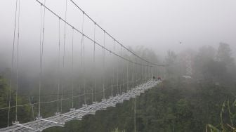 Sejumlah pekerja memasang kerangka besi saat membangun jembatan gantung di lereng Gunung Merapi, Tegalmulyo, Kemalang, Klaten, Jawa Tengah, Sabtu (18/12/2021). [ANTARA FOTO/Aloysius Jarot Nugroho]