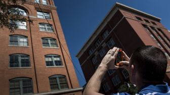 Dalam file foto yang diambil pada tanggal (9/10/2013) menunjukkan seorang pria memotret lantai 6 Gedung Administrasi Wilayah Dallas yang sebelumnya menampung Penyimpanan Buku Sekolah Texas di Dallas, Texas, tempat pembunuhan Presiden AS John F. Kennedy. [BRENDAN SMIALOWSKI / AFP]