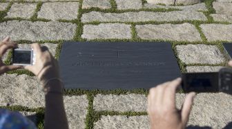 Dalam file foto yang diambil pada tanggal (24/9/2013) menunjukkan wisatawan memotret makam mantan Presiden AS John F. Kennedy di Arlington National Cemetery, Arlington, Virginia, Amerika Serikat. [BRENDAN SMIALOWSKI / AFP]