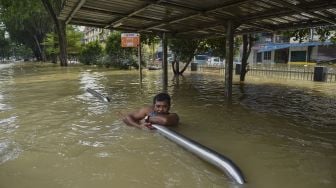 Seorang pria berpegangan pada besi pembatas menunggu untuk dievakuasi oleh tim penyelamat di Shah Alam, Selangor, Malaysia, Senin (20/12/2021). [ARIF KARTONO / AFP]