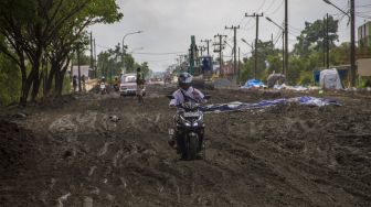 Pengendara sepeda motor melintas di jalan Trans Kalimantan yang rusak di Kecamatan Liang Anggang, Banjarbaru, Kalimantan Selatan, Minggu (19/12/2021). [ANTARA FOTO/Bayu Pratama S]