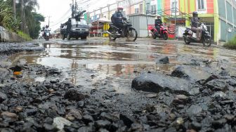 Sejumlah kendaraan melintasi jalan berlubang dan tergenang air di Jalan Raya Tegar Beriman, Cibinong, Kabupaten Bogor, Jawa Barat, Selasa (21/12/2021).  ANTARA FOTO/Yulius Satria Wijaya