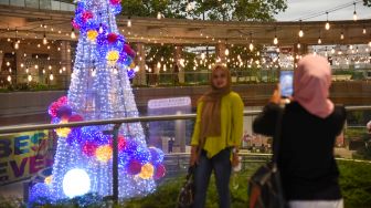 Pengunjung berswafoto dengan latar belakang pohon Natal setinggi 12 meter di salah satu pusat perbelanjaan di Medan,� Sumatera Utara, Selasa (21/12/2021). ANTARA FOTO/Fransisco Caroli