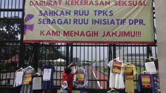 Massa yang tergabung dalam Jaringan Pembela Hak Perempuan Korban Kekerasan Seksual memasang instalasi pakaian korban kekerasan seksual saat melakukan aksi unjuk rasa di depan Gedung DPR, Jakarta, Rabu (22/12/2021). [Suara.com/Angga Budhiyanto]