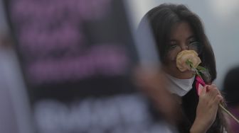 Massa yang tergabung dalam Jaringan Pembela Hak Perempuan Korban Kekerasan Seksual membawa bunga saat melakukan aksi unjuk rasa di depan Gedung DPR, Jakarta, Rabu (22/12/2021). [Suara.com/Angga Budhiyanto]