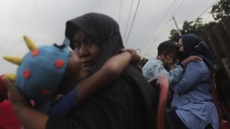 Dua orang ibu memeluk anaknya usai mengikuti acara Cuci Kaki Ibu Massal di Kelurahan Duri Pulo, Gambir, Jakarta, Rabu (22/12/2021). [Suara.com/Angga Budhiyanto]