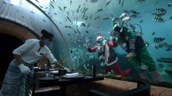 Dua orang penyelam berkostum Sinterklas dan Elf memberi makan ikan di dalam akuarium Koral Restaurant, The Apurva Kempinski Bali, Badung, Bali, Kamis (23/12/2021). ANTARA FOTO/Fikri Yusuf