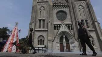 Personel kepolisian berjaga di depan Gereja Katedral, Jakarta, Jumat (24/12/2021). [Suara.com/Angga Budhiyanto]