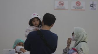 Orang tua mendaftarkan anaknya untuk melakukan tes usap PCR di Stasiun Pasar Senen, Jakarta, Jumat (24/12/2021). [Suara.com/Angga Budhiyanto]