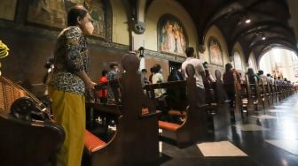 Umat Kristiani berdoa saat mengikuti Misa Natal di Gereja Katedral, Jakarta Pusat, Sabtu (25/12/2021). [Suara.com/Alfian Winanto,]