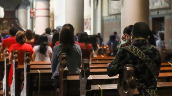 Umat Kristiani berdoa saat mengikuti Misa Natal di Gereja Katedral, Jakarta Pusat, Sabtu (25/12/2021). [Suara.com/Alfian Winanto,]