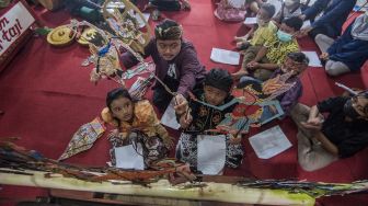 Dalang Indra Suroinggeno (tengah) memainkan wayang kulit bertema Natal di Bantul, Yogyakarta, pada (24/12/2021). [AGUNG SUPRIYANTO / AFP]