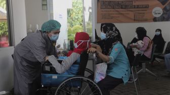 Petugas kesehatan memeriksa kesehatan warga yang akan melakukan tes usap (swab test) antigen di Puskesmas Kecamatan Mampang Prapatan, Jakarta Selatan, Senin (27/12/2021). [Suara.com/Angga Budhiyanto]