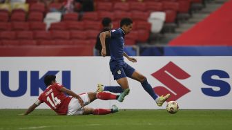 Pemain Indonesia Asnawi Mangkualam Bahar (kiri) berebut bola dengan pemain Thailand Bordin Phala pada pertandingan leg pertama final sepak bola Piala AFF Suzuki 2020 antara Indonesia dan Thailand di Stadion Nasional Singapura, Rabu (29/12/2021). [ROSLAN RAHMAN / AFP]