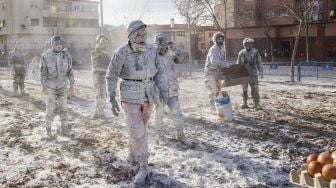 Orang-orang yang bersuka ria mengenakan pakaian militer mengambil bagian dalam pertempuran "Els Enfarinats" di Kota Ibi, Spanyol, pada (28/12/2021). [JAIME REINA / AFP]