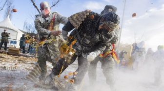 Orang-orang yang bersuka ria mengenakan pakaian militer mengambil bagian dalam pertempuran "Els Enfarinats" di Kota Ibi, Spanyol, pada (28/12/2021). [JAIME REINA / AFP]