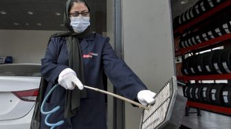 Seorang mekanik perempuan Saudi membersihkan onderdil mobil di bengkel perbaikan dan servis di kota pesisir Laut Merah, Arab Saudi, Jeddah, pada (27/12/2021). [AMER HILABI / AFP]