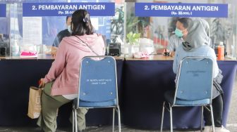 Penumpang membayar untuk Rapid Tes Antigen di Stasiun Gambir, Jakarta Pusat, Sabtu (1/1/2022). [Suara.com/Alfian Winanto]