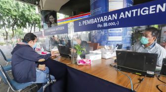 Penumpang membayar untuk Rapid Tes Antigen di Stasiun Gambir, Jakarta Pusat, Sabtu (1/1/2022). [Suara.com/Alfian Winanto]