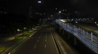 Suasana sepi saat malam pergantian tahun di Jalan Sudirman, Jakarta Pusat, Sabtu (1/1/2022). [Suara.com/Alfian Winanto]