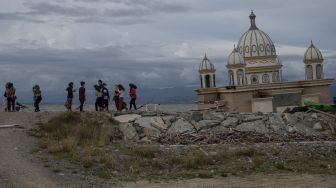 Sejumlah warga menyaksikan Masjid Terapung yang ambruk ke laut akibat tsunami di Pantai Kampung Lere, Palu, Sulawesi Tengah, Sabtu (1/1/2021). [ANTARA FOTO/Basri Marzuki]