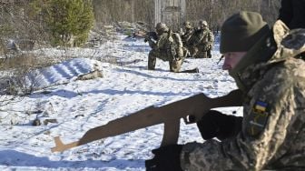 Pasukan Pertahanan Teritorial Ukraina yang merupakan cadangan militer Angkatan Bersenjata Ukraina, memegang replika kayu senapan Kalashnikov selama latihan militer di dekat Kiev, Ukraina, pada (25/12/2021). [SERGEI SUPINSKY / AFP]